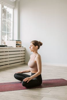 Young woman meditating in a serene indoor setting, promoting mindfulness and wellness.