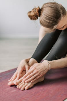 Close-up of woman in black sportswear doing yoga stretch indoors for fitness and flexibility.