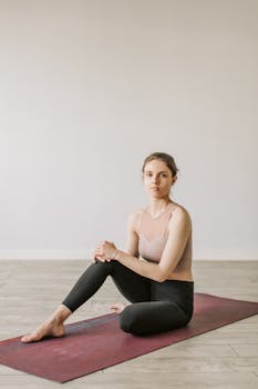 A young woman practicing yoga indoors, seated on a mat, promoting a healthy lifestyle.