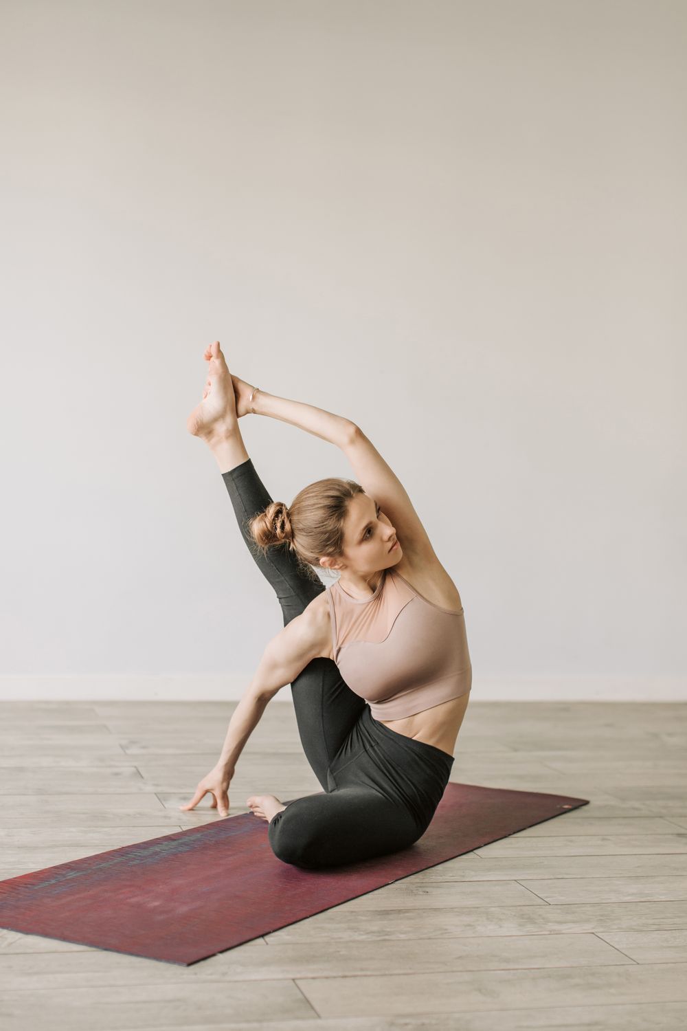 A Woman Stretching Her Leg while Sitting on a Yoga Mat · Free Stock Photo