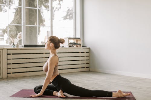 A Woman Stretching Her Leg while Sitting on a Yoga Mat