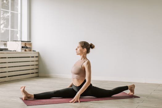 Adult woman stretching on a yoga mat indoors, demonstrating flexibility and focus.