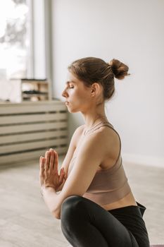 Calm woman with closed eyes practicing yoga indoors for mindfulness and well-being.