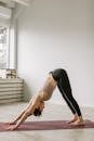白天，成年女性在室内垫子上练习面朝下的狗式瑜伽