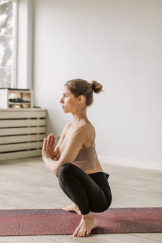 Serene woman practicing yoga squat indoors, embodying mindfulness and tranquility.