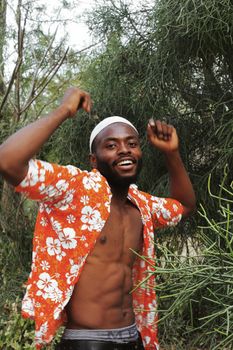 一个开朗的男人穿着充满活力的花卉衬衫，在大自然中精力充沛地跳舞
