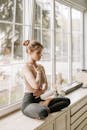 一位年轻女子在阳光明媚的窗边，以宁静的瑜伽姿势练习冥想