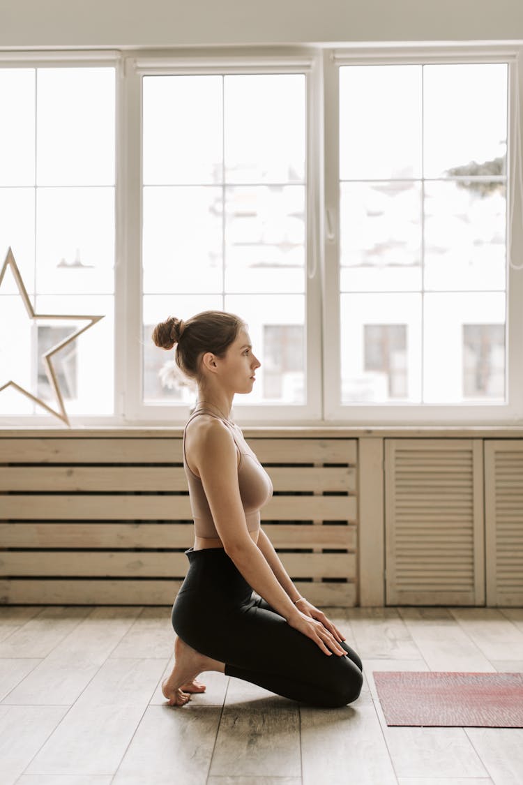 A Woman In Black Leggings Kneeling On The Floor