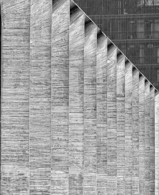 Black and white row of tall columns of huge grey industrial building in daylight