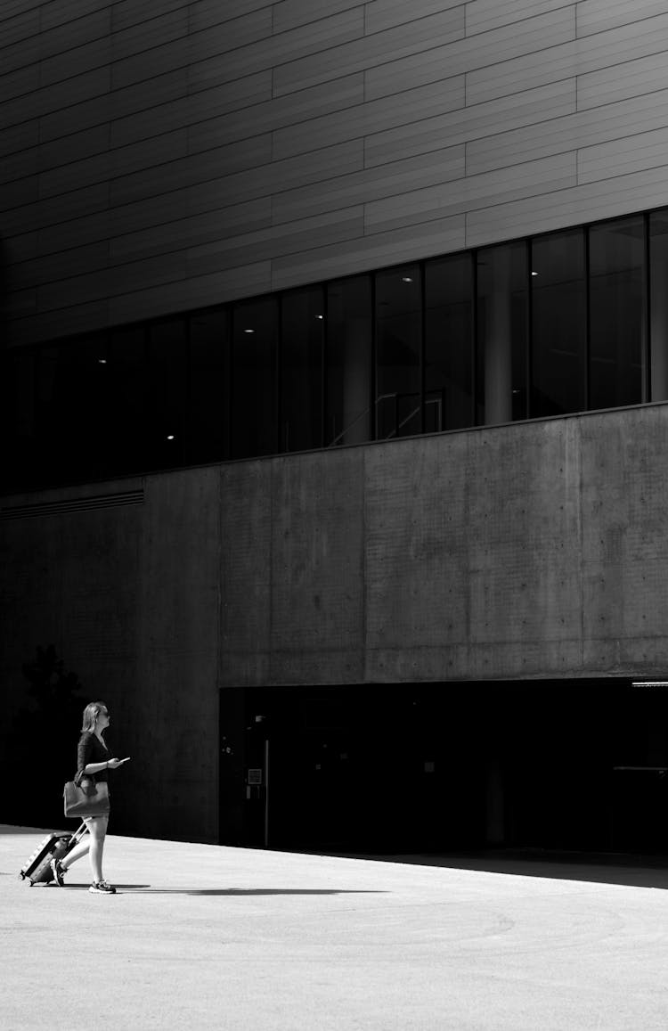 Female Tourist Walking To Entrance Of High Building