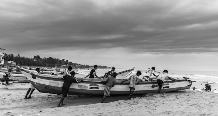 Grayscale Photo Of People Pushing A Boat