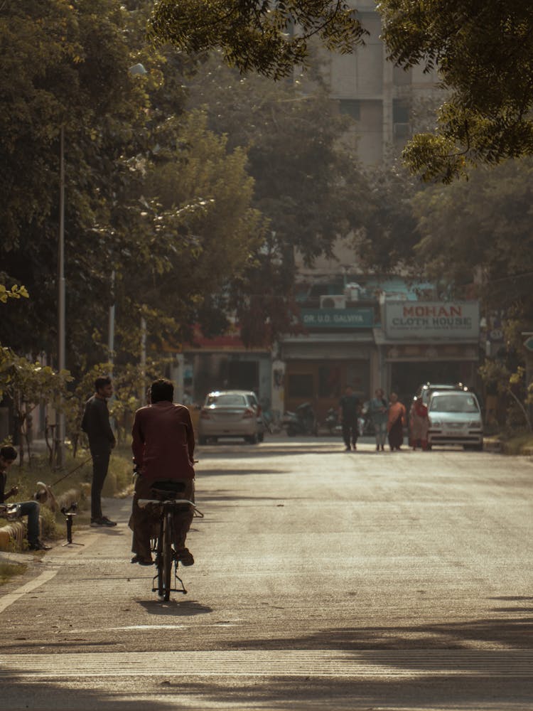 Unrecognizable Man Riding Bicycle On City Road