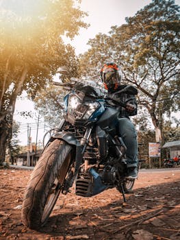 Motorcyclist on a street road with trees, in bright daylight, showcasing modern biking gear.