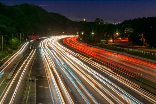 Free Bright city road between mountains under sky at night Stock Photo