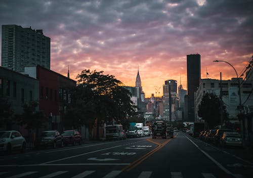 Road between modern buildings under bright sky in night city