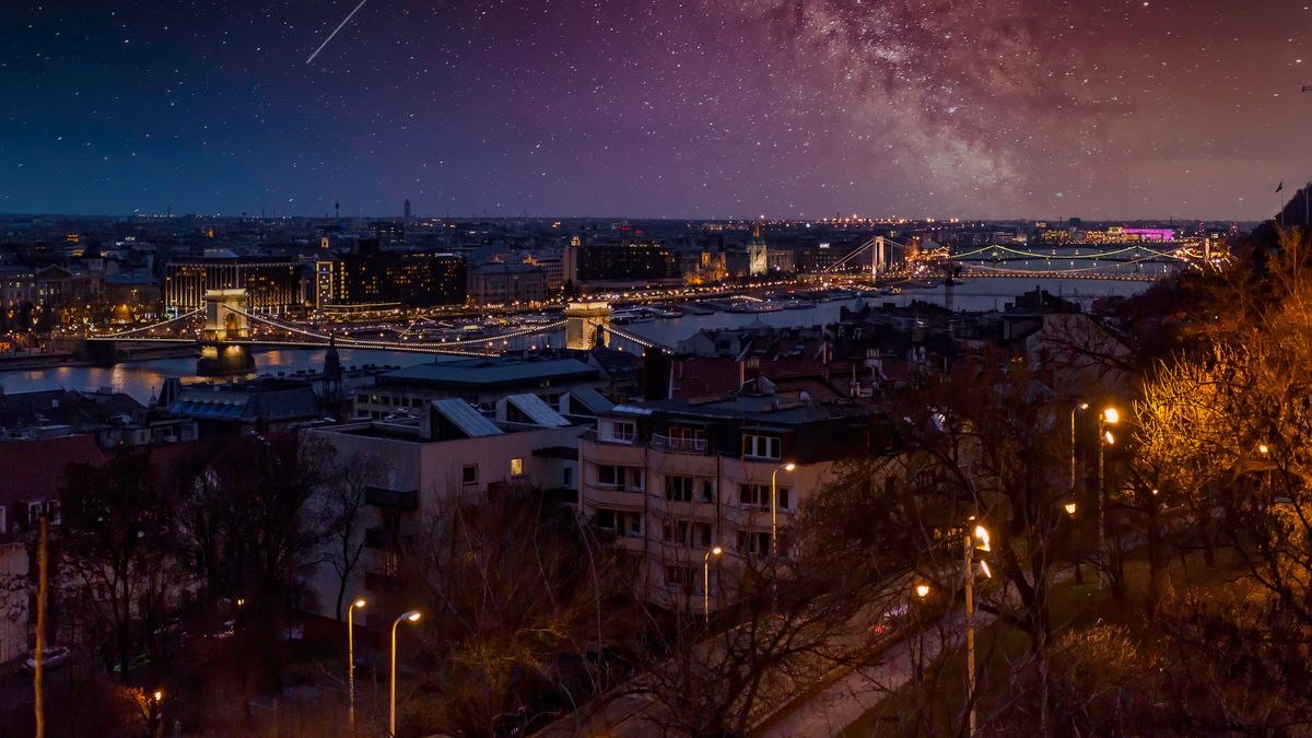 From above of house facades near river and lamp posts with glowing lights under sky in town at dusk