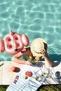 Woman in Green and White Floral Bikini Top Wearing Brown Sun Hat on Swimming Pool during