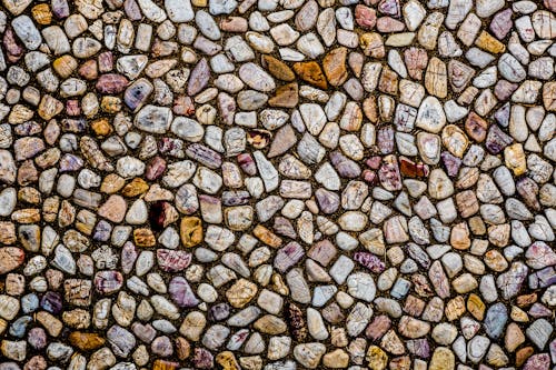 Top view of textured background representing pebble shore with bright small stones in summer