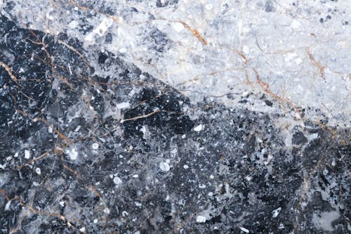 Closeup of abstract background of textured natural stone formation with cracks and white spots