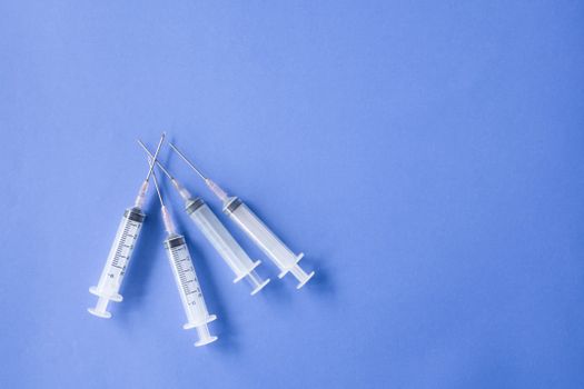 蓝色表面上排列的医用注射器堆的俯视图平面构成