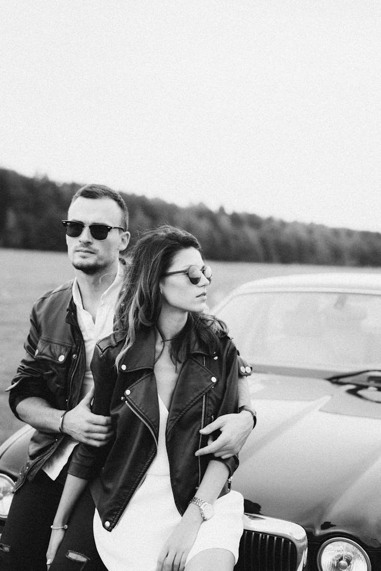 Young Couple Sitting On Car 