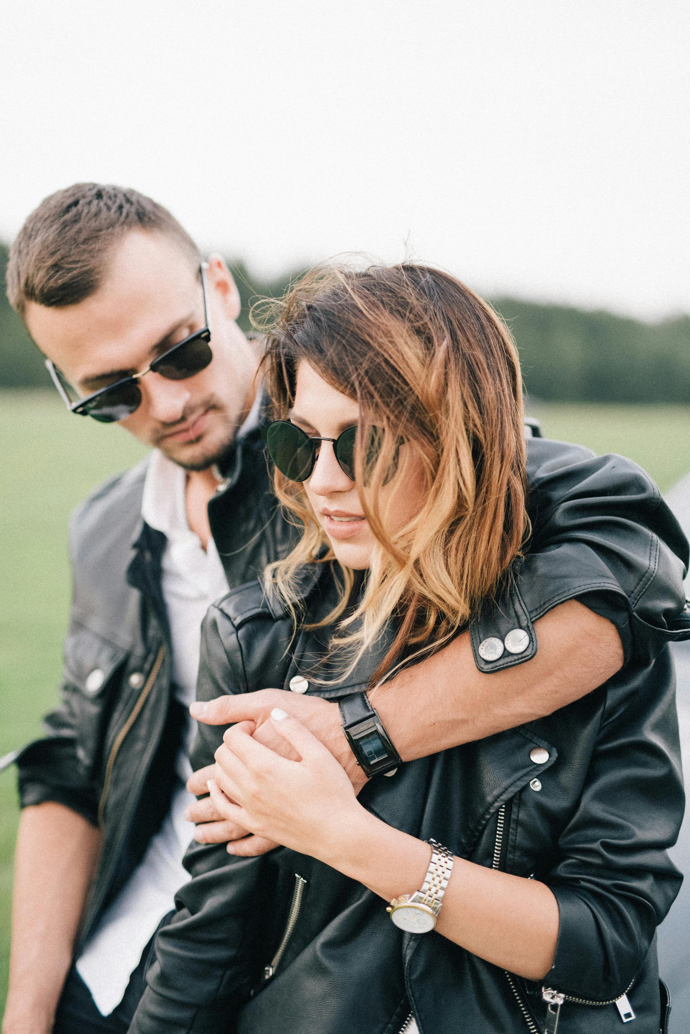 Stylish couple in sunglasses embracing near luxury car in countryside ...