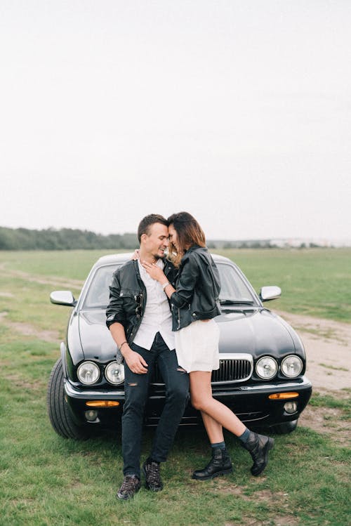 An Affectionate Couple Standing in front of a Black Car