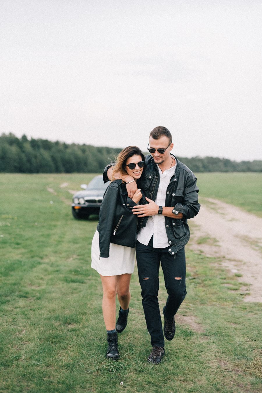 Couple wearing black leather jackets in a field