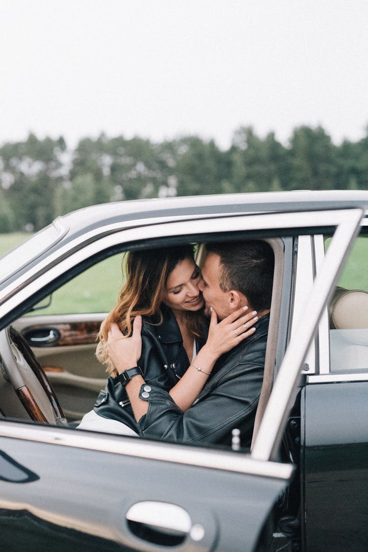 An Affectionate Couple Hugging Inside A Black Car