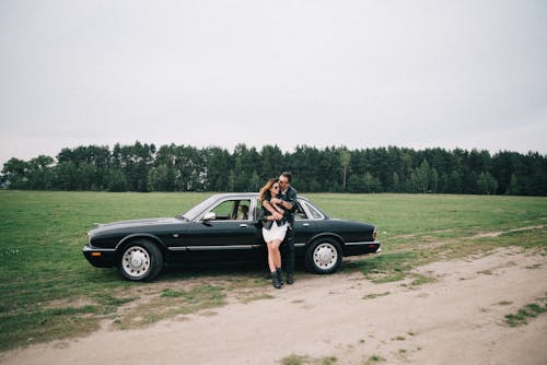 A Couple Standing by a Black Car in the Countryside