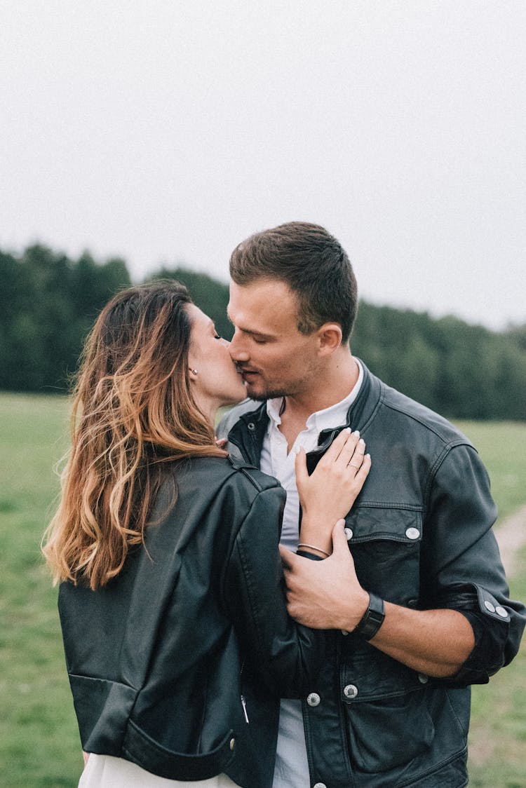 A Couple In Black Leather Jackets Kissing In The Countryside