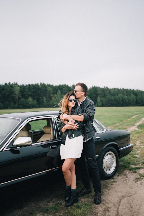 A Couple Posing by a Black Car in the Countryside