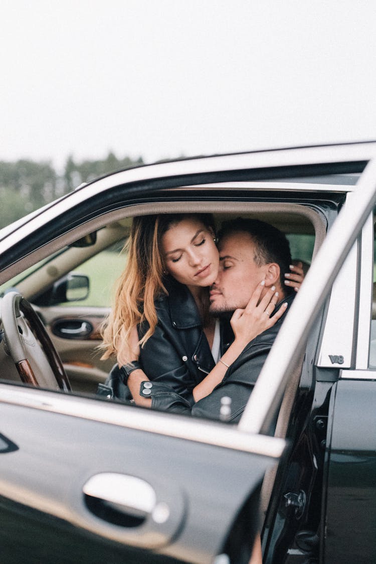 A Couple Hugging Inside A Black Car