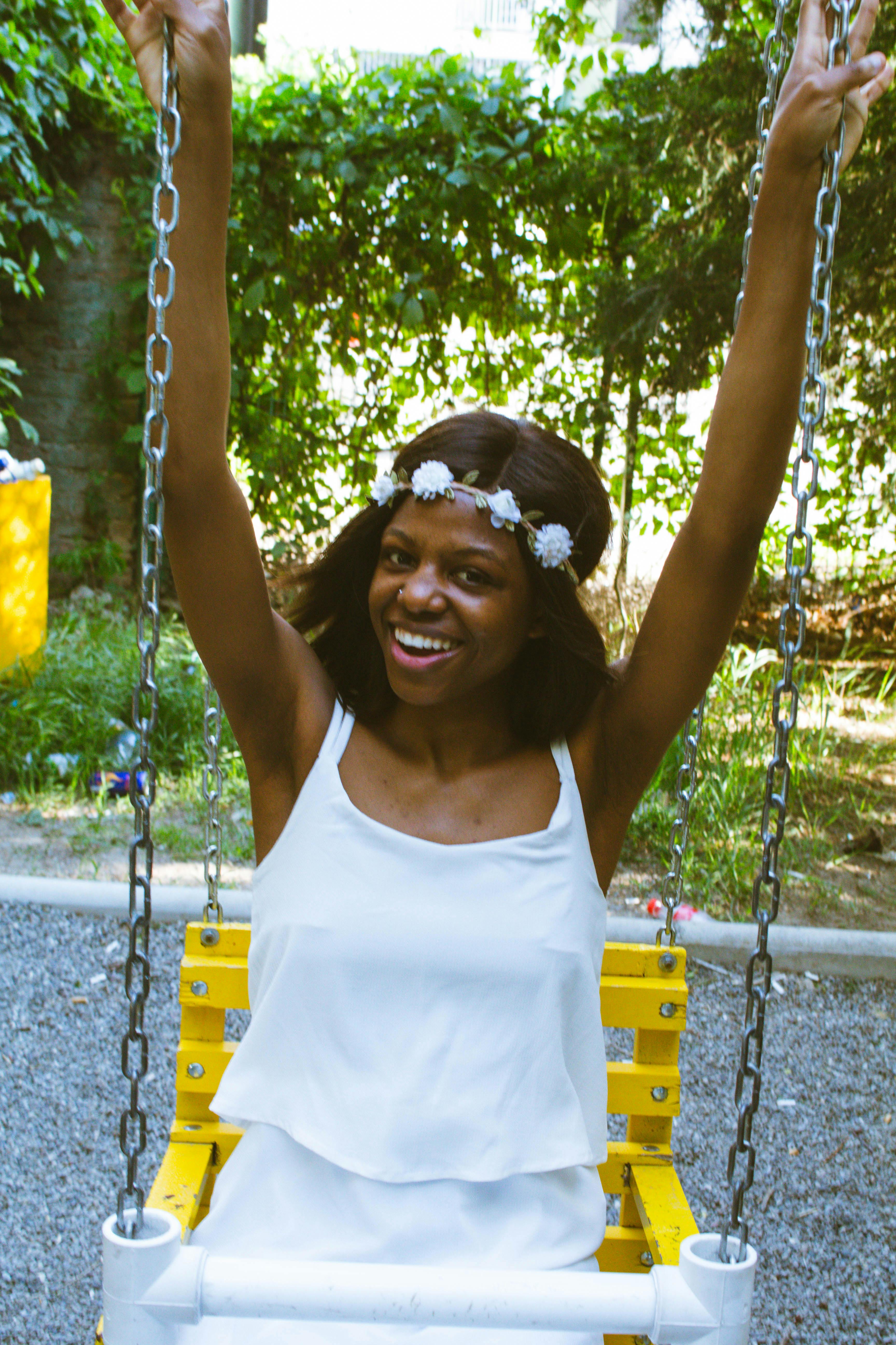 joyful young african american female swinging in playground