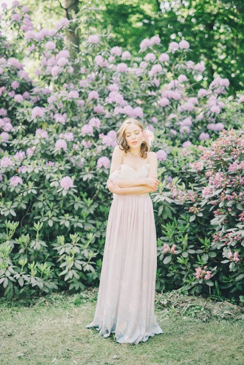 Femme En Robe Jaune Debout Devant Des Fleurs Violettes