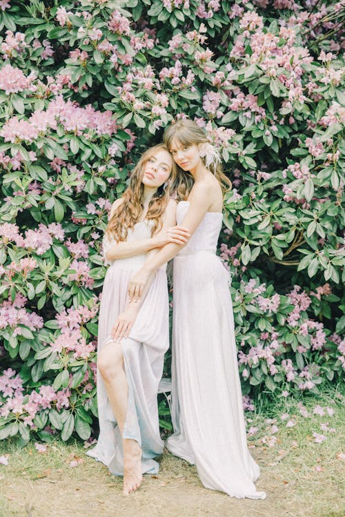 Mulher Em Vestido Branco Sem Mangas Em Pé Ao Lado De Flores Cor De Rosa