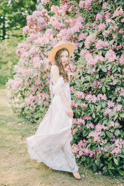 Femme En Robe Blanche Debout à Côté De Fleurs Roses