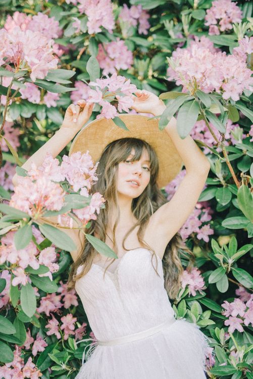 Pretty Woman Wearing a Hat Leans on Pink Flowers · Free Stock Photo