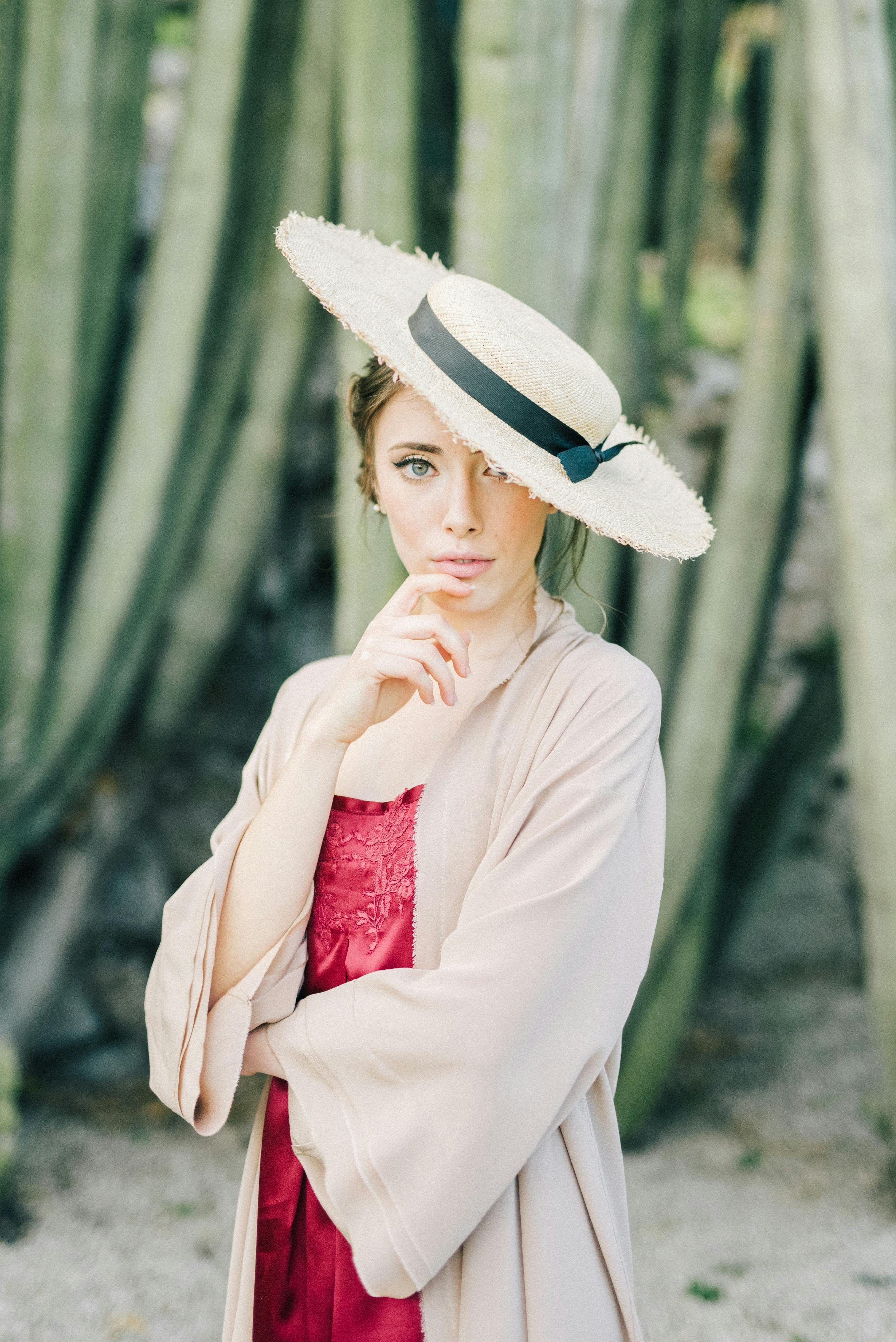 Stylish portrait of a woman in a straw hat posed against a natural background, conveying elegance.