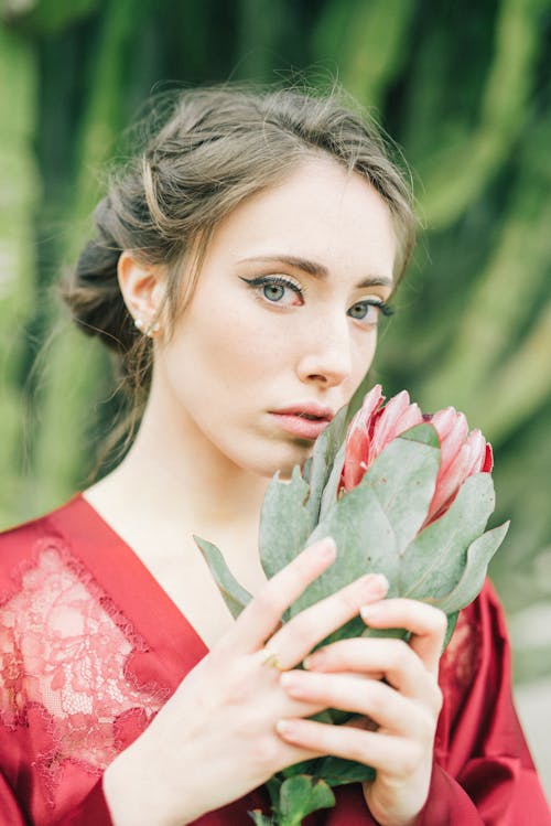A Woman Holding Red Flower with Green Leaves
