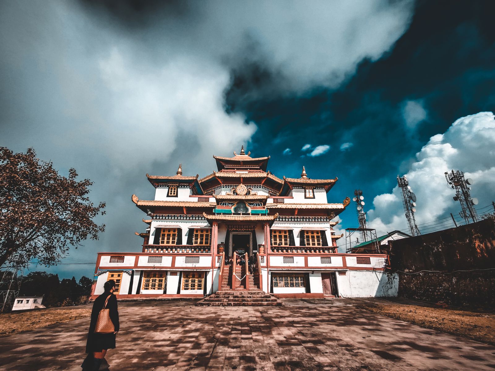 A Tibetan Buddhist monastery in Kalimpong with white walls and tiered gilded roofs under dark cloud