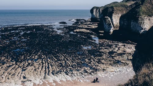 From above of blue ocean surrounded with rocky cliffs at low tide at Selwicks Bay in Flamborough