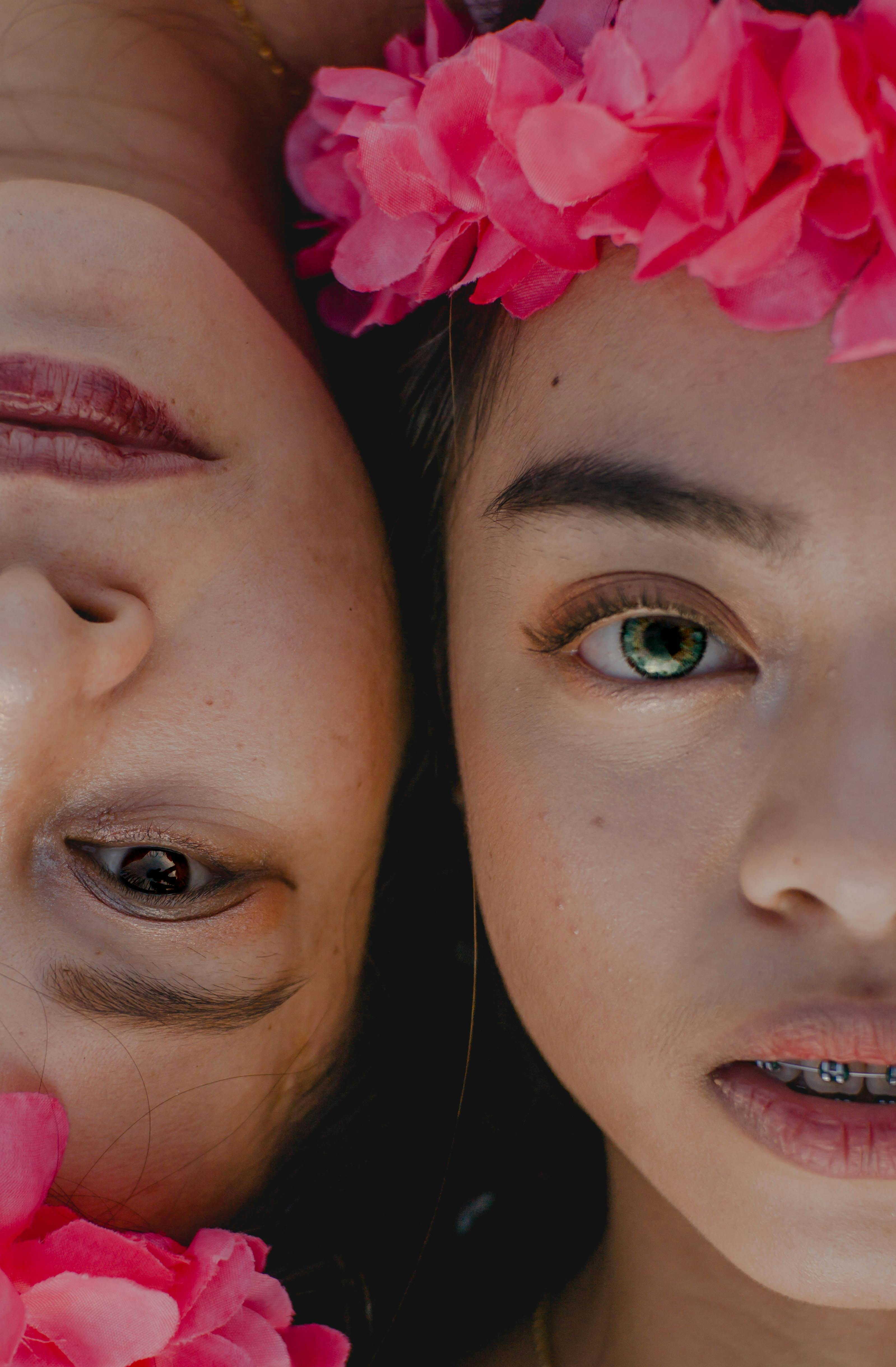 Close-up portrait of two women adorned with pink floral headbands, exuding a peaceful elegance.