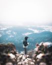 Man in Black Jacket Standing on Rock Looking at the Mountains