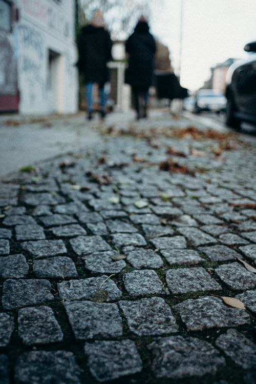 Free Close-up of cobblestone path with blurred figures walking in urban setting, creating a vibrant city atmosphere. Stock Photo