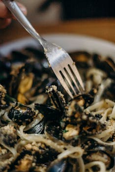 Appetizing close-up of spaghetti with mussels and a fork, showcasing Italian cuisine.