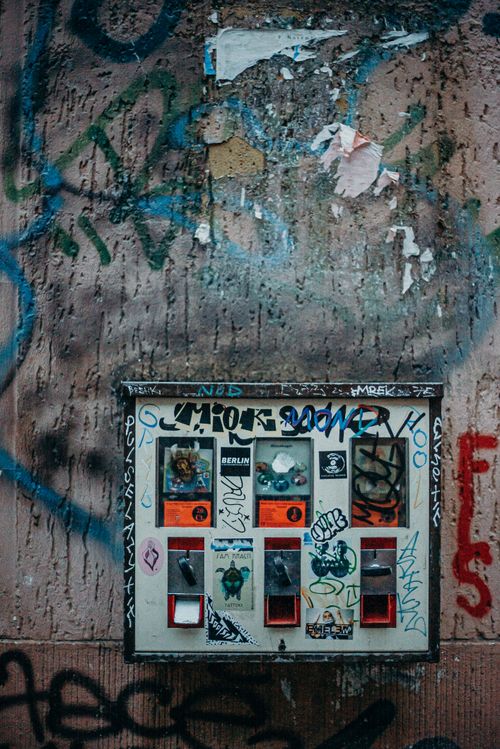 Free Vending machine with vibrant graffiti on a Berlin street. Urban city life scene. Stock Photo