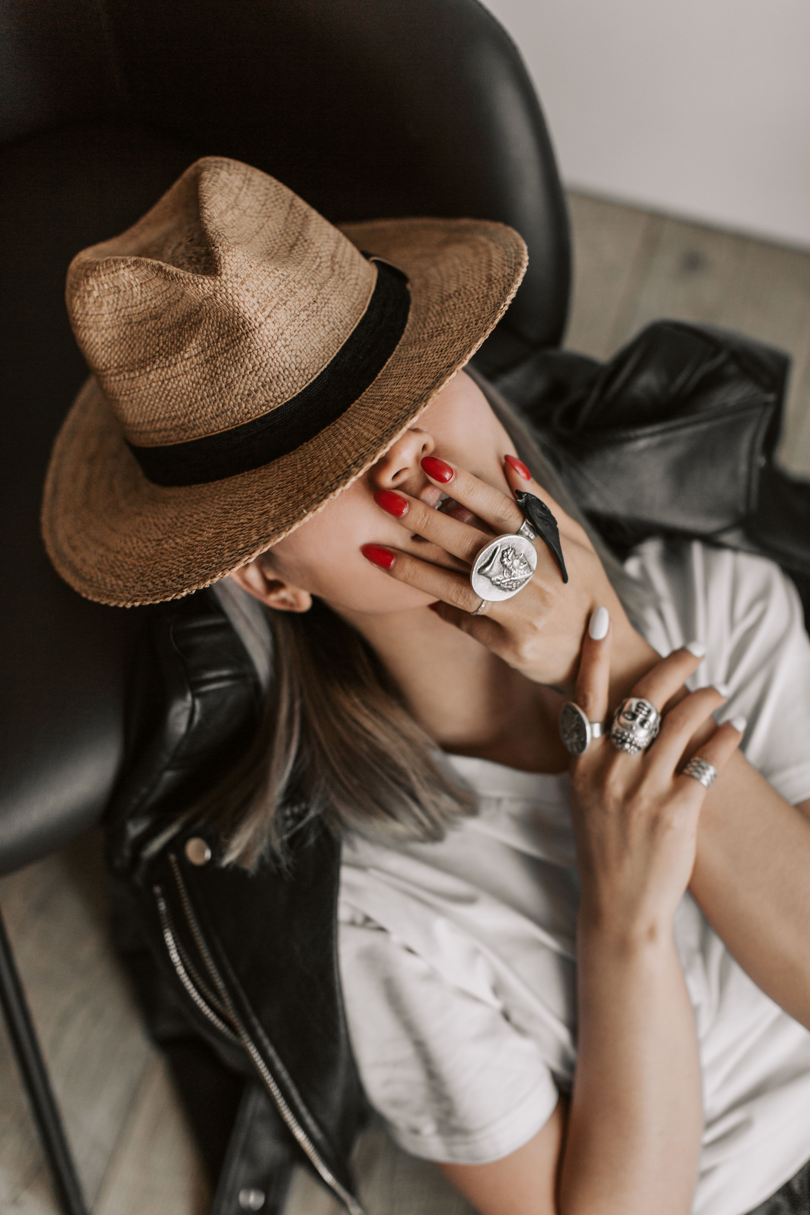 Mulher fashionista com chapéu e anéis, posando em um estilo chique em uma fotografia interna.