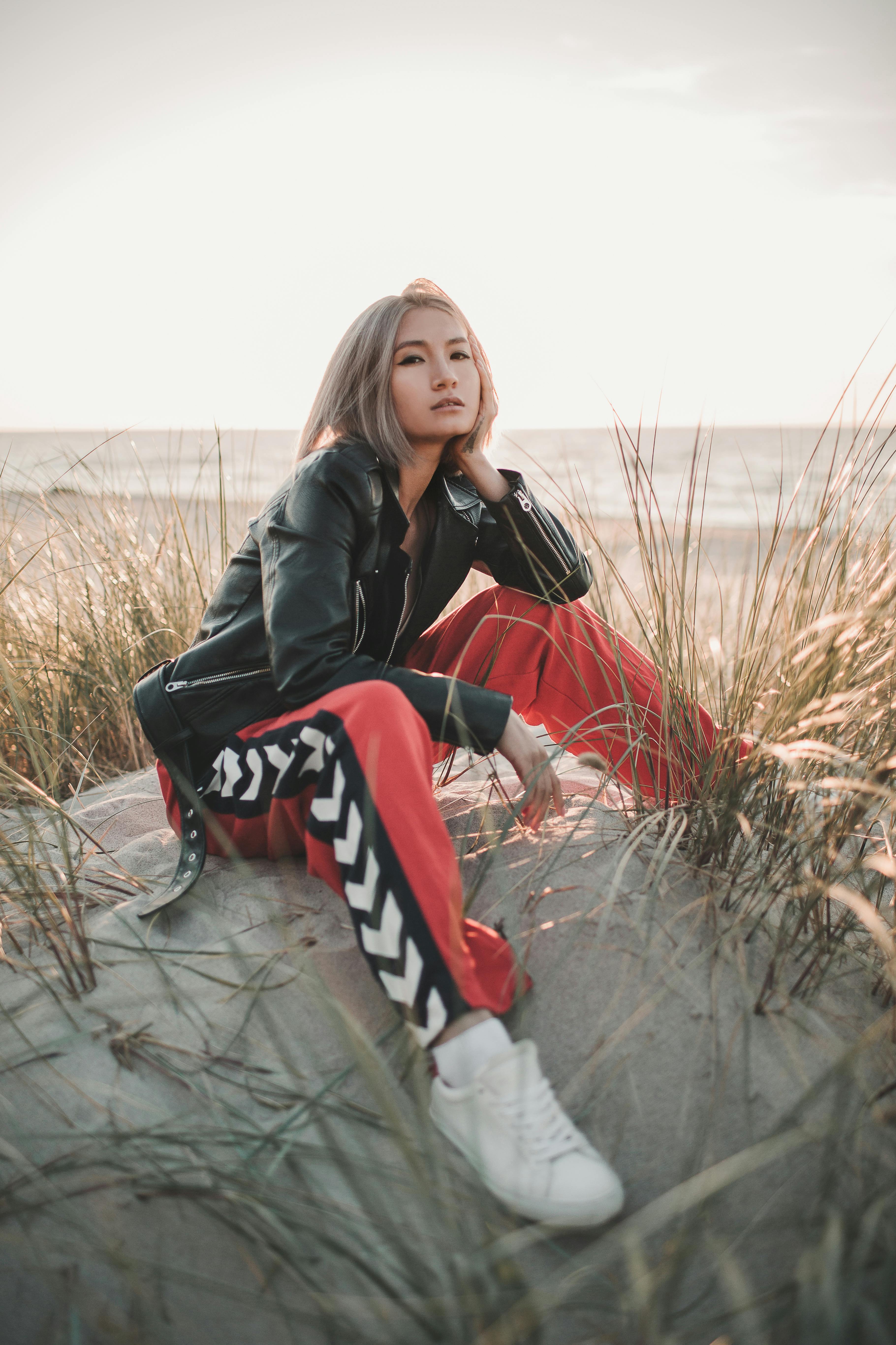 a woman in black leather jacket and red pants