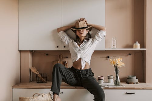 A Woman in White Long Shirt Sitting on Kitchen Counter
